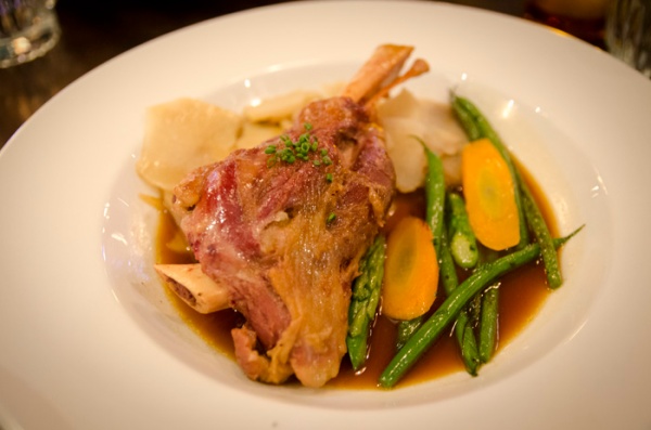 Rosemary braised lamb shank with string beans, carrots, sliced potatoes in a braising jus